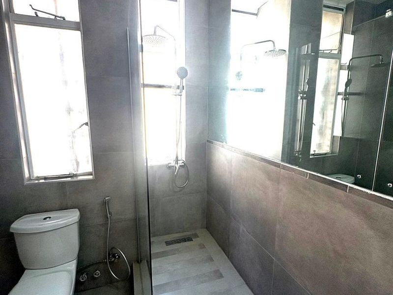 Modern bathroom featuring a walk-in shower with glass screen, large wall mirror, tiled finishes, and contemporary sanitary ware.