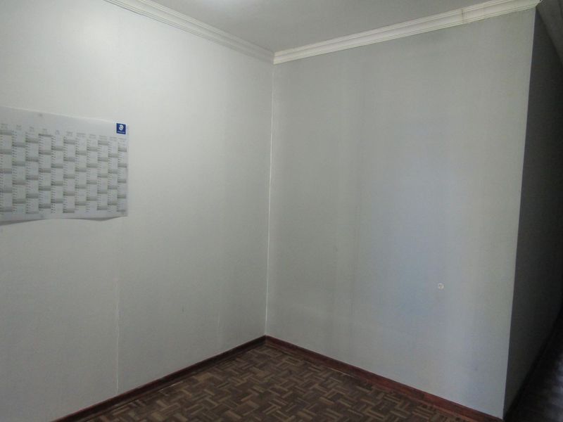 An empty bedroom featuring parquet flooring and simple cornice detailing, presenting a blank canvas for potential renovation or interior design updates.
