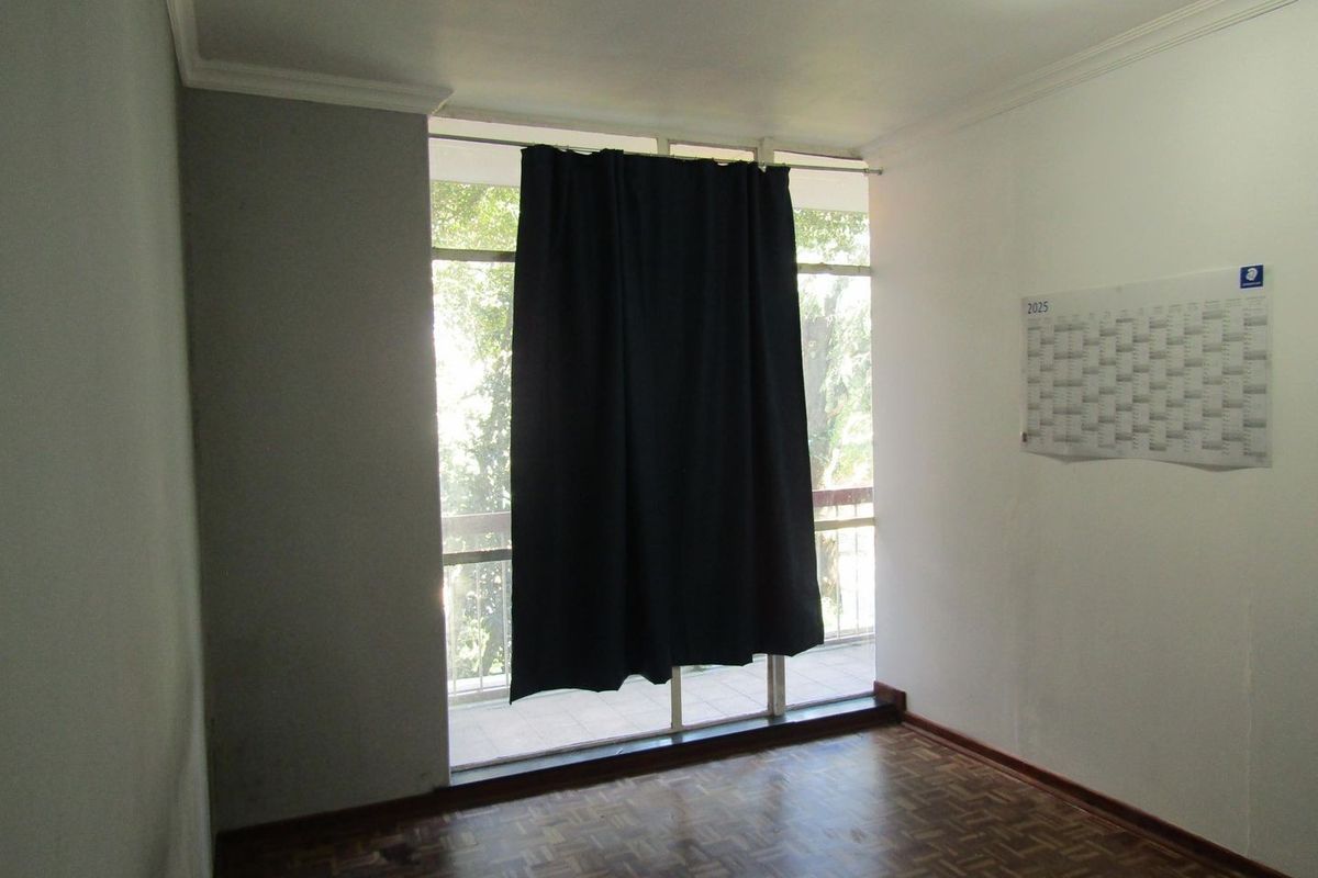 An empty bedroom featuring parquet flooring, coving, and a large floor-to-ceiling window providing access to an outdoor balcony area.