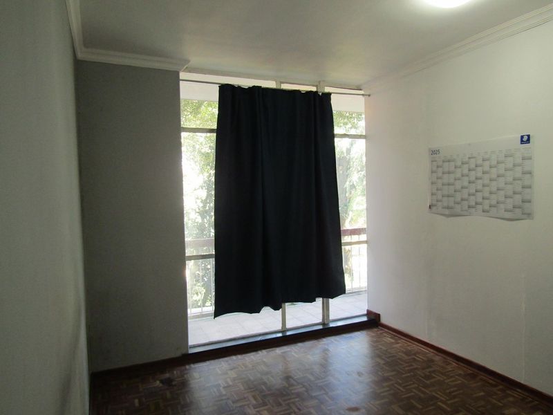 An empty bedroom featuring parquet flooring, coving, and a large floor-to-ceiling window providing access to an outdoor balcony area.