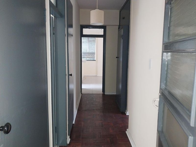 A functional hallway featuring classic parquet flooring, built-in storage cupboards, and access to adjacent rooms.