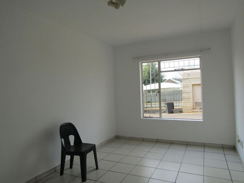A bright, empty bedroom featuring neutral white walls and clean tiled flooring, ready for personalization.