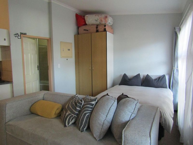 Compact open-plan studio apartment featuring a combined living and sleeping area with a built-in wardrobe and direct access to an en-suite bathroom.