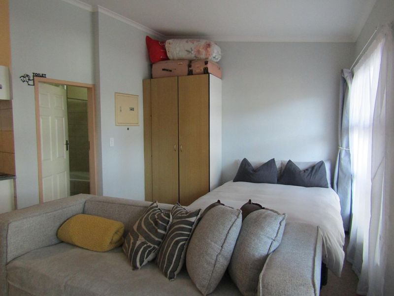 Compact open-plan studio apartment featuring a combined living and sleeping area with built-in storage and direct access to an en-suite bathroom.