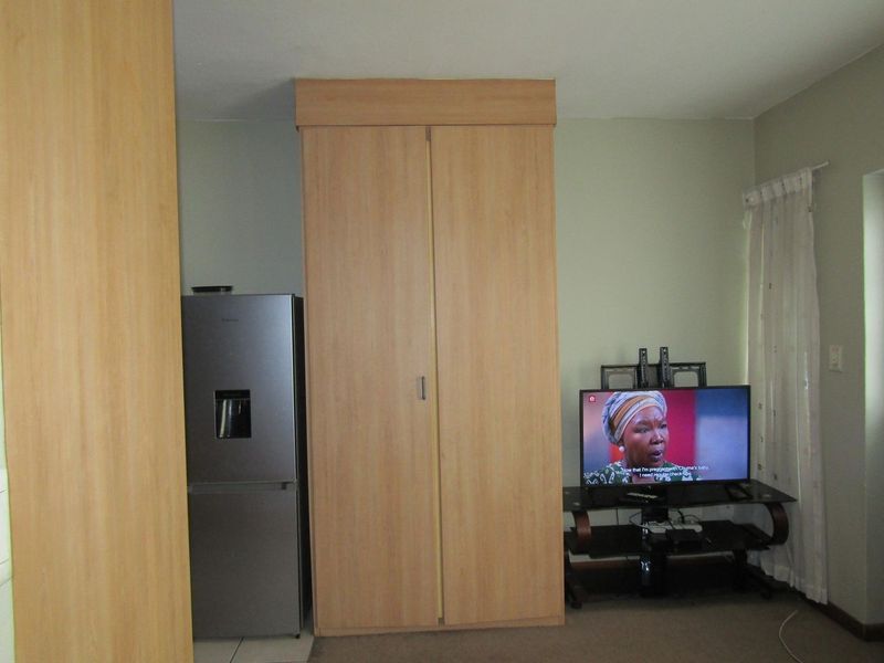 A bedroom featuring a light wood-finish built-in wardrobe and neutral wall tones.