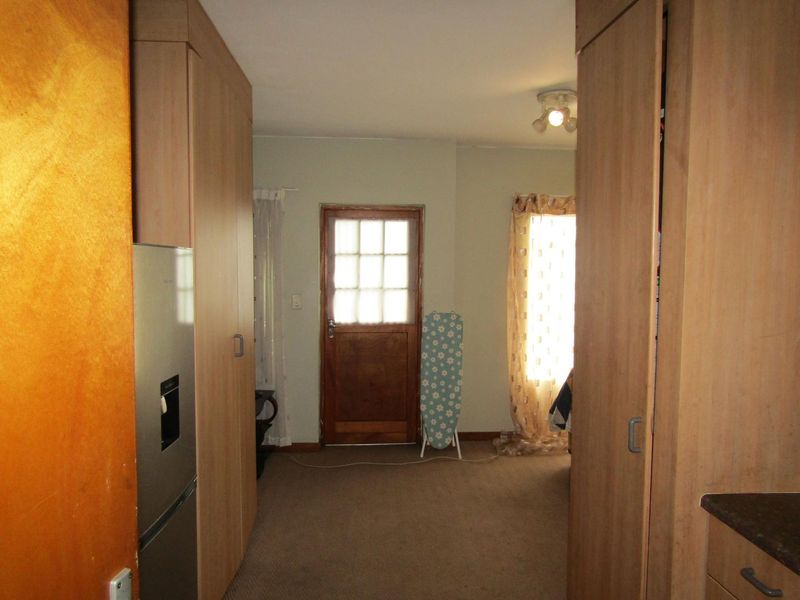 A functional kitchen area featuring built-in wooden cabinetry, laminate countertops, and direct access to an exterior door.