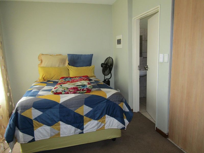 A functional bedroom featuring carpeted flooring, a built-in wardrobe, and direct access to an en-suite bathroom.