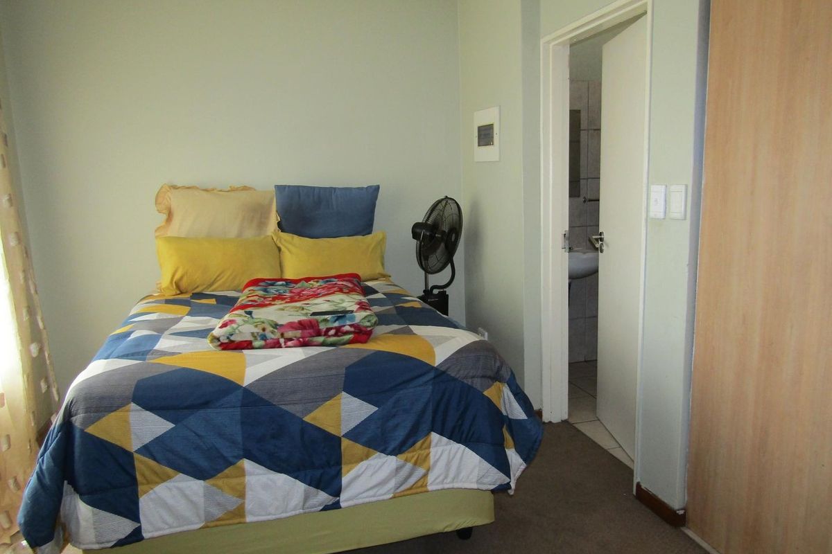 A functional bedroom featuring carpeted flooring, a built-in wardrobe, and direct access to an en-suite bathroom.