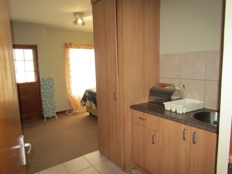Open plan living area featuring a compact kitchenette with built-in cabinetry, laminate countertops, and a stainless steel sink.