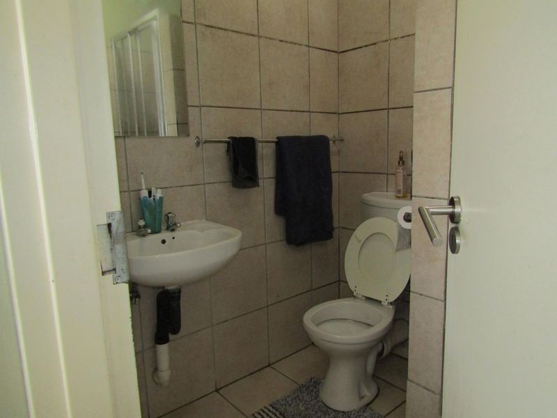 A compact bathroom featuring ceramic wall and floor tiles, a wall-mounted basin, and a standard toilet.