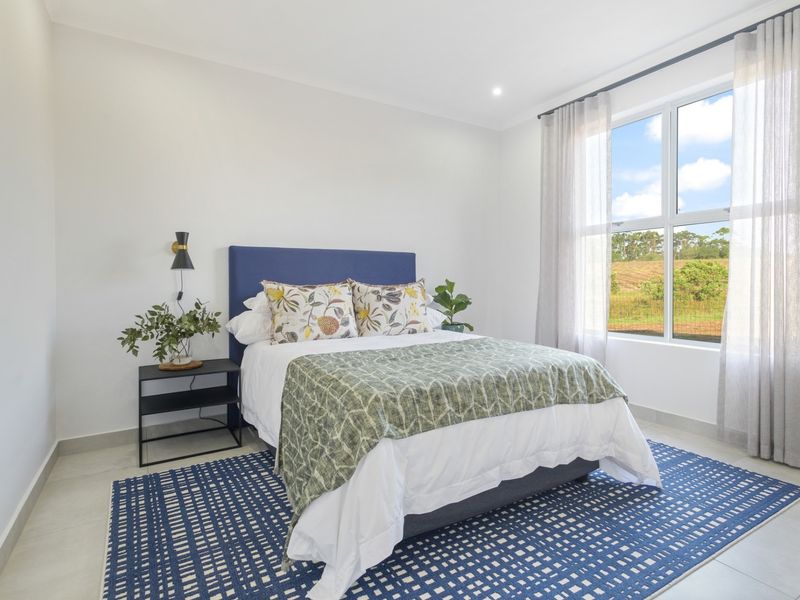 A bright and modern bedroom featuring neutral tiled flooring, recessed lighting, and a large window providing natural light and scenic views.