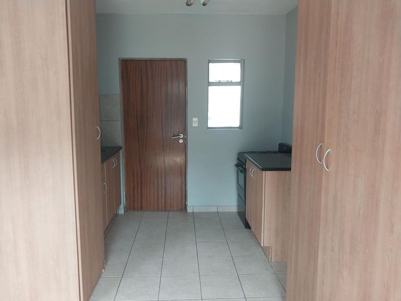 A functional kitchen area featuring built-in cabinetry, laminate countertops, a freestanding stove, and tiled flooring, providing a clean and practical workspace.