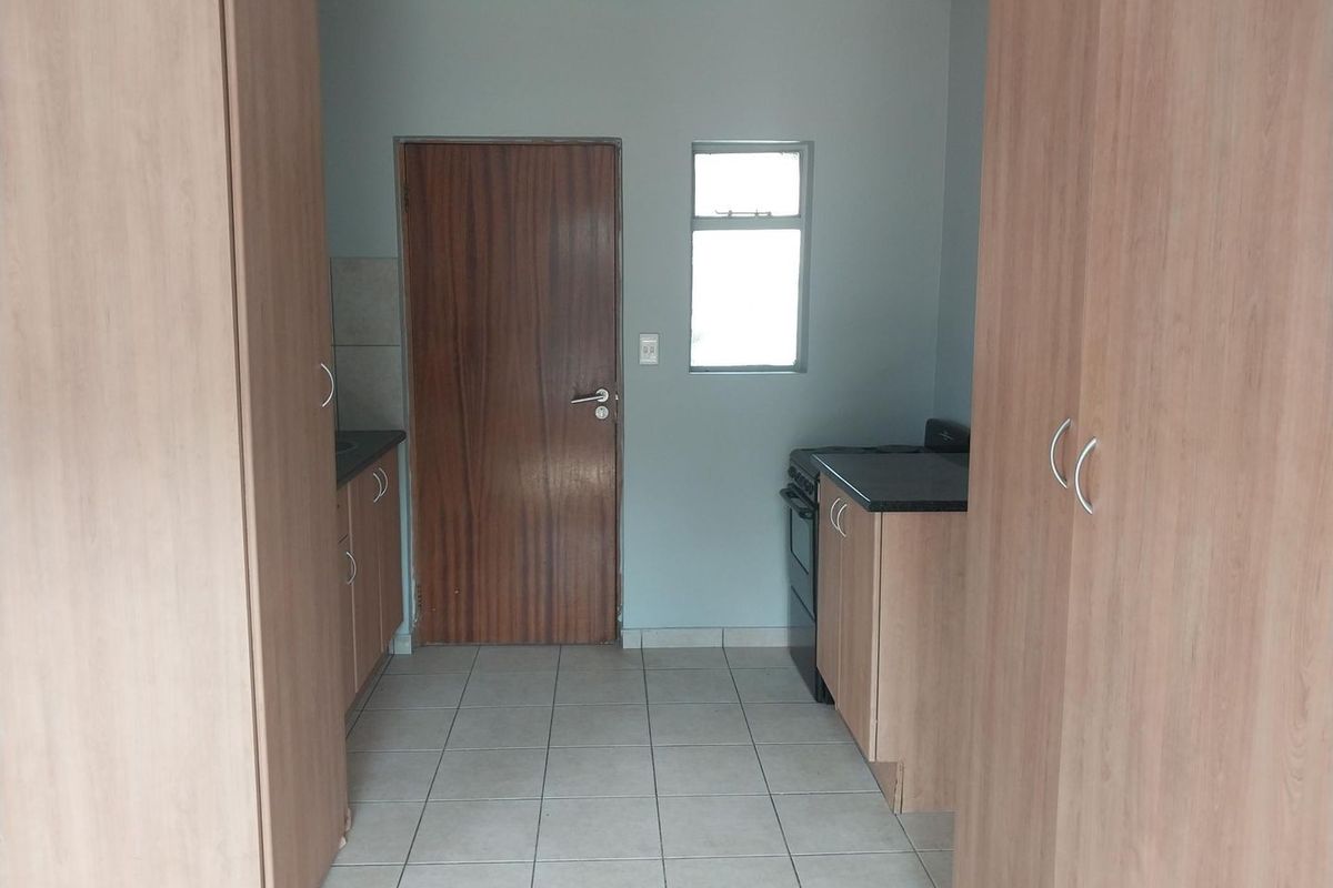 A functional kitchen area featuring built-in cabinetry, laminate countertops, a freestanding stove, and tiled flooring, providing a clean and practical workspace.