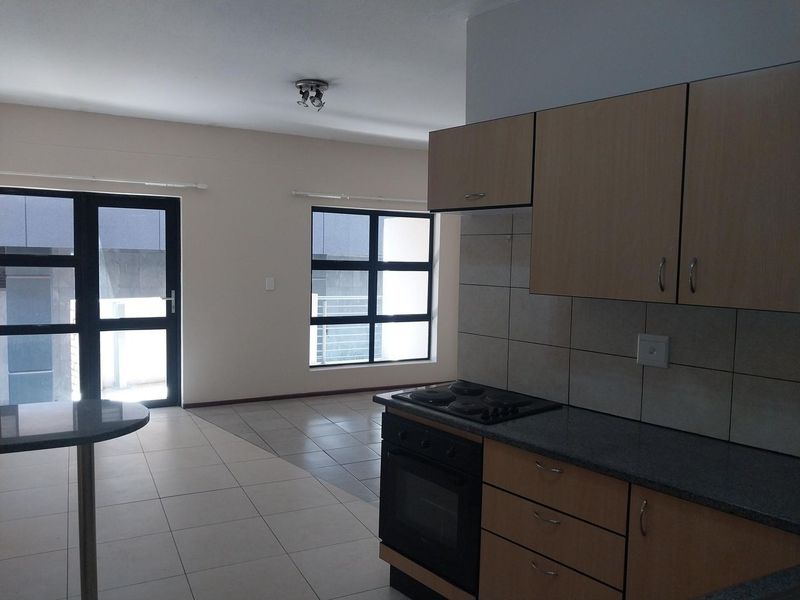 Open-plan kitchen and living area featuring tiled floors, built-in cabinetry with granite countertops, and direct access to an outdoor balcony.