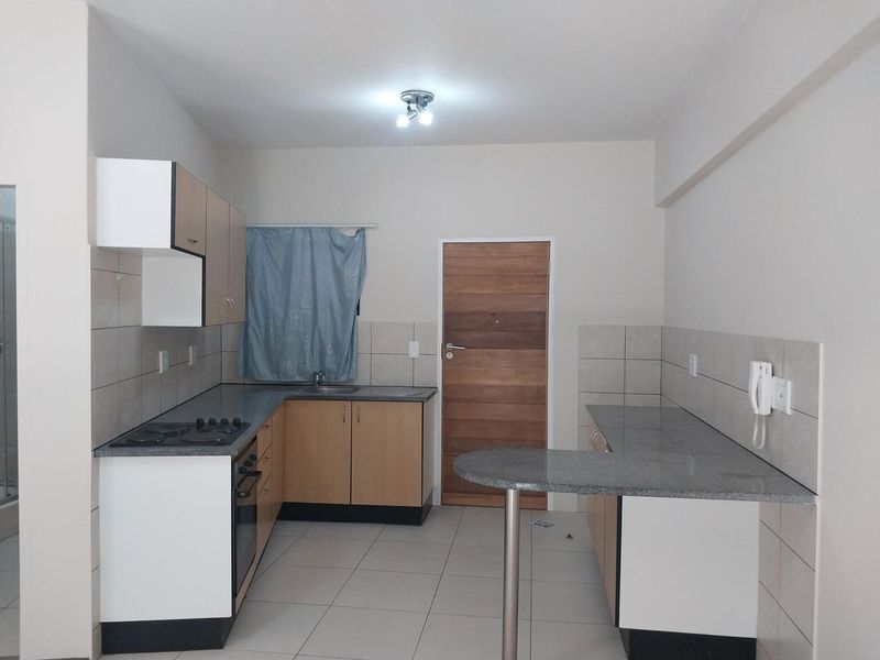 A functional kitchen featuring built-in cabinetry, laminate countertops, a gas hob, built-in oven, and a breakfast bar with tiled flooring and backsplash.