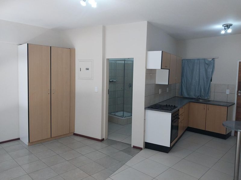 Open plan kitchen and living area featuring built-in cabinetry, hob, oven, and tiled flooring, with an adjacent bathroom access.