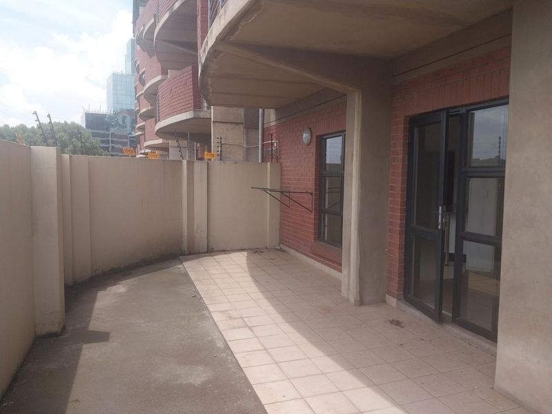 A private ground-floor patio featuring tiled flooring, a brick facade, and direct access to the interior through sliding glass doors.