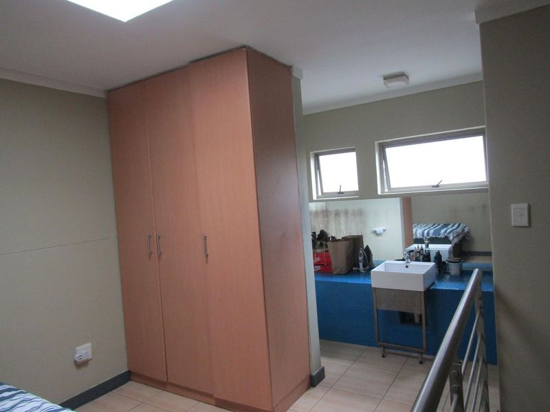 Bedroom featuring built-in wardrobe storage and an integrated vanity area with a wall-mounted basin and large mirror.
