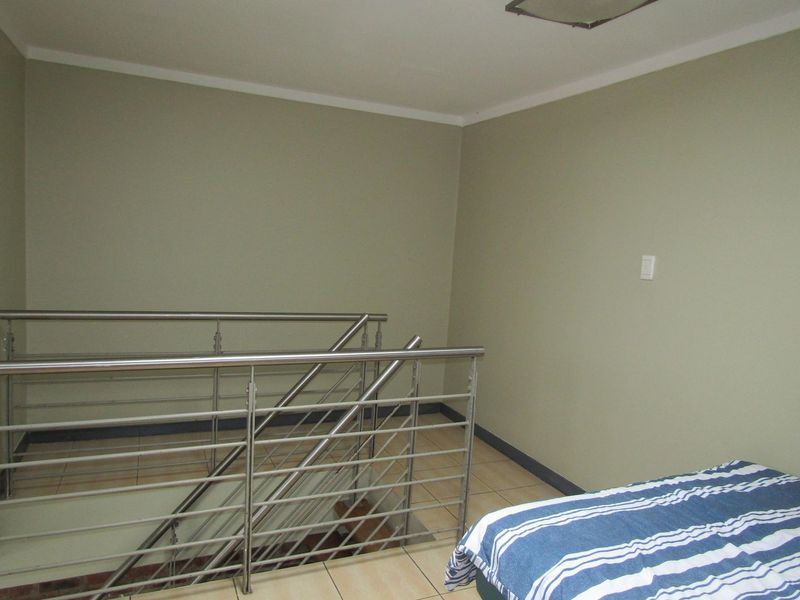 Upper level landing area featuring tiled flooring and a modern stainless steel balustrade overlooking the staircase.
