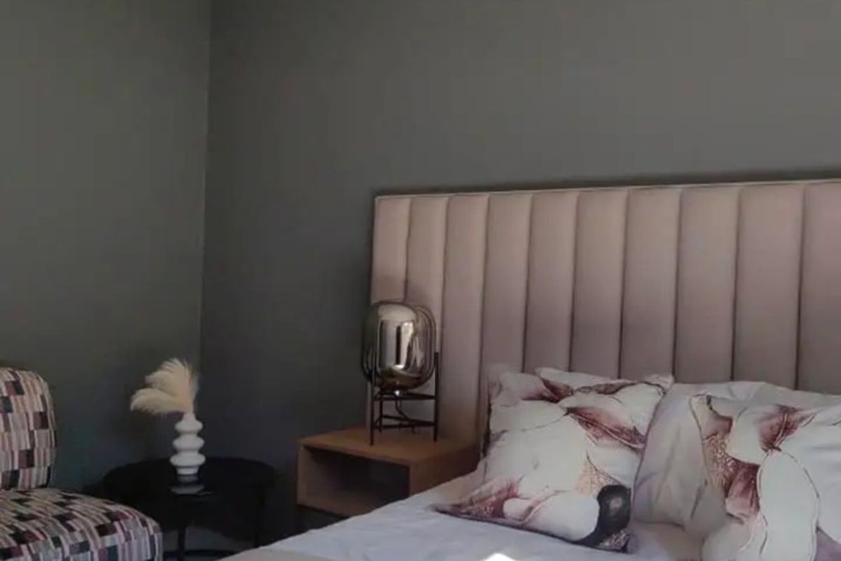A well-maintained bedroom featuring a modern upholstered headboard and neutral grey wall finishes.