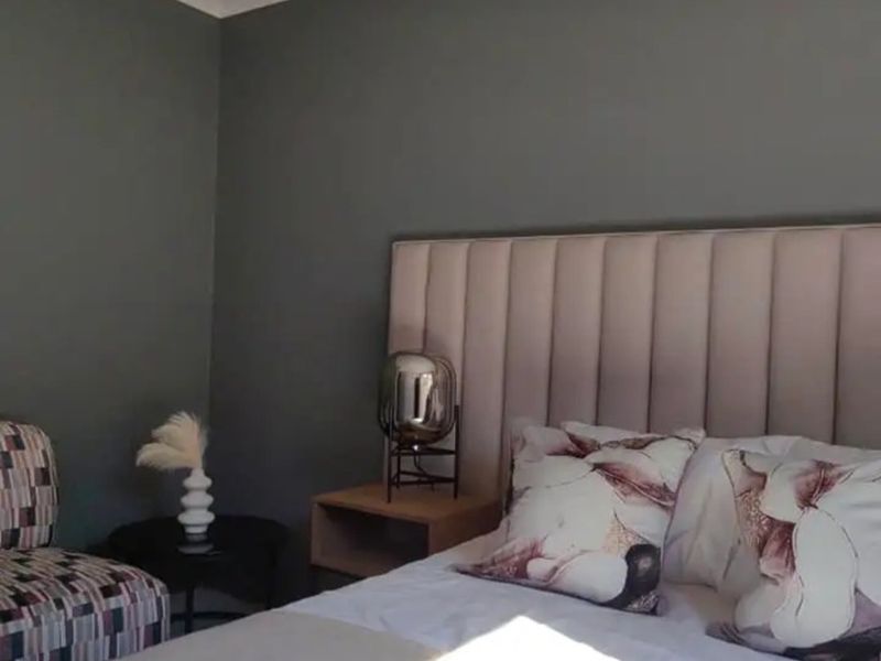 A well-maintained bedroom featuring a modern upholstered headboard and neutral grey wall finishes.