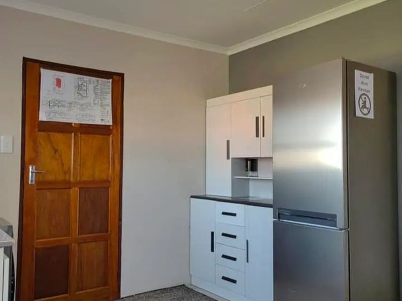 A compact kitchen area featuring white built-in cabinetry, a dark countertop, and a wooden door.