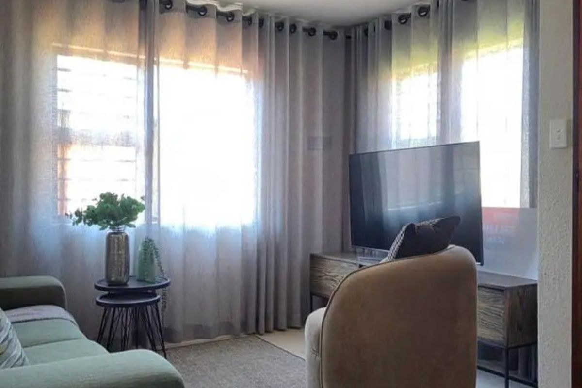 A cozy living room area featuring large windows with installed curtain tracks and neutral wall finishes.