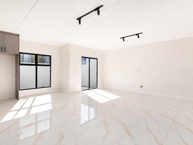 A bright, modern, and spacious living area featuring polished marble-look porcelain tiles, contemporary track lighting, and direct access to an outdoor space.