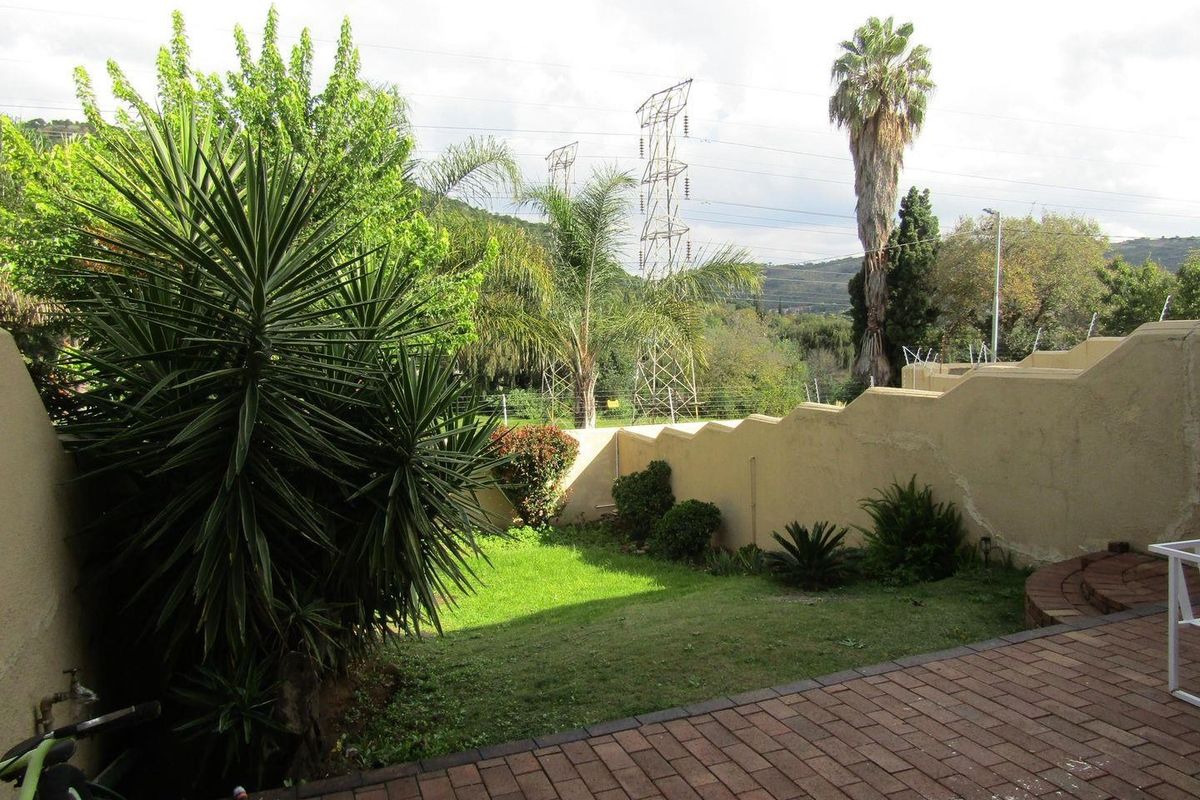 A private rear garden featuring brick paving, a lawn area, and a boundary wall with electric fencing.