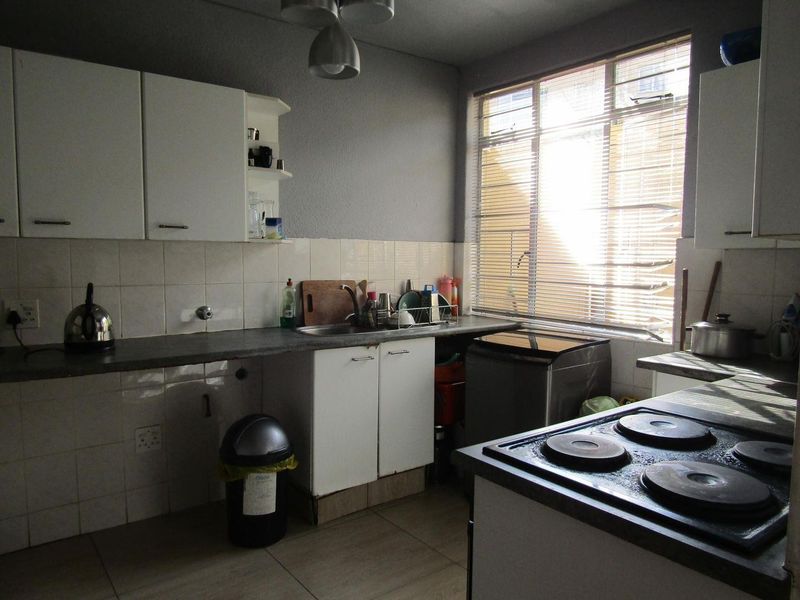 Functional kitchen featuring built-in cabinetry, tiled backsplash, electric hob, and ample natural light from the window.