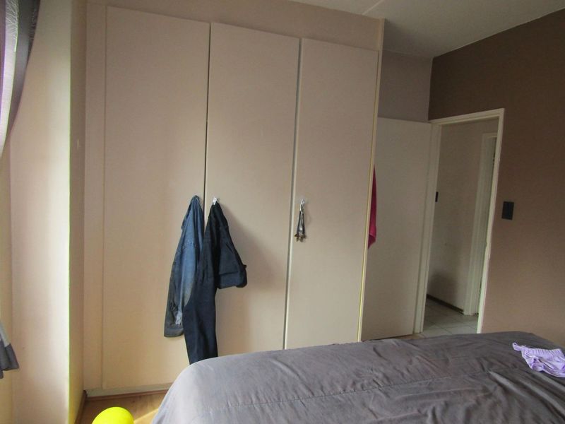 A bedroom featuring built-in cupboards and neutral wall finishes.