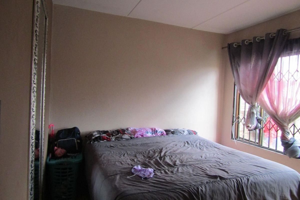 A standard bedroom featuring a window with a fitted security gate and curtain rod, providing natural light and basic security.