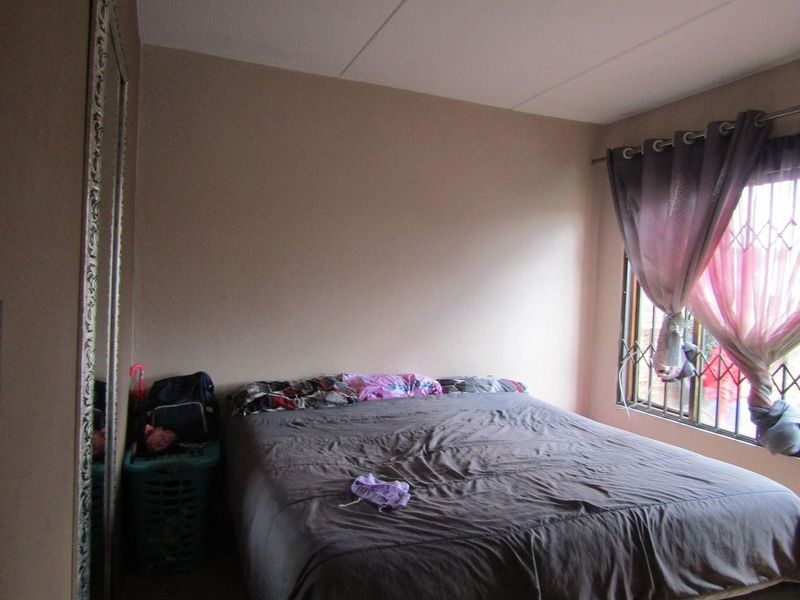 A standard bedroom featuring a window with a fitted security gate and curtain rod, providing natural light and basic security.
