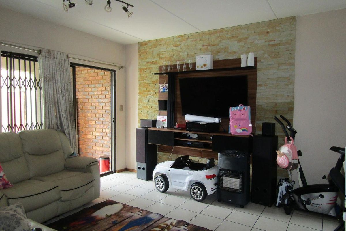 Living room featuring a stone accent wall, tiled flooring, and sliding glass door access to the exterior.