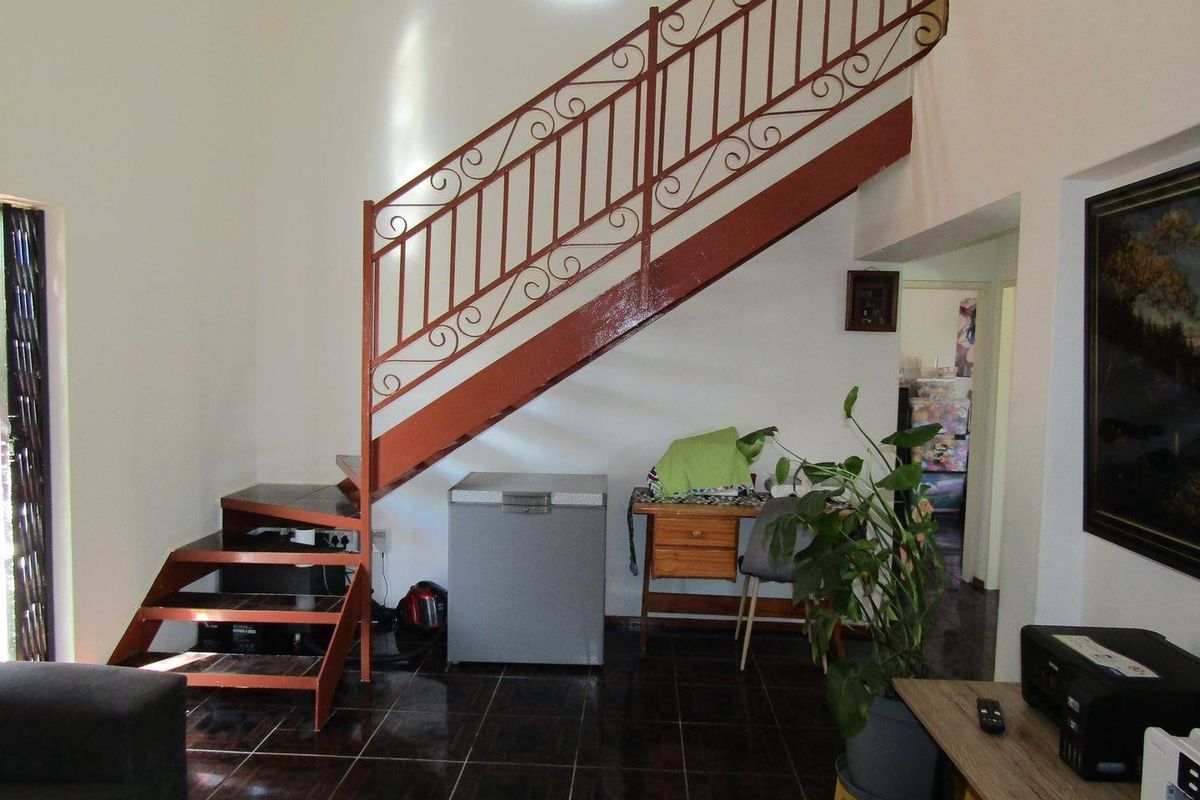Living area featuring a prominent metal staircase with decorative wrought iron balustrade and dark tiled flooring.