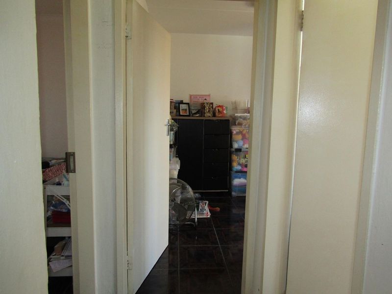 A view through a hallway connecting multiple rooms, featuring dark tiled flooring and standard internal door frames.