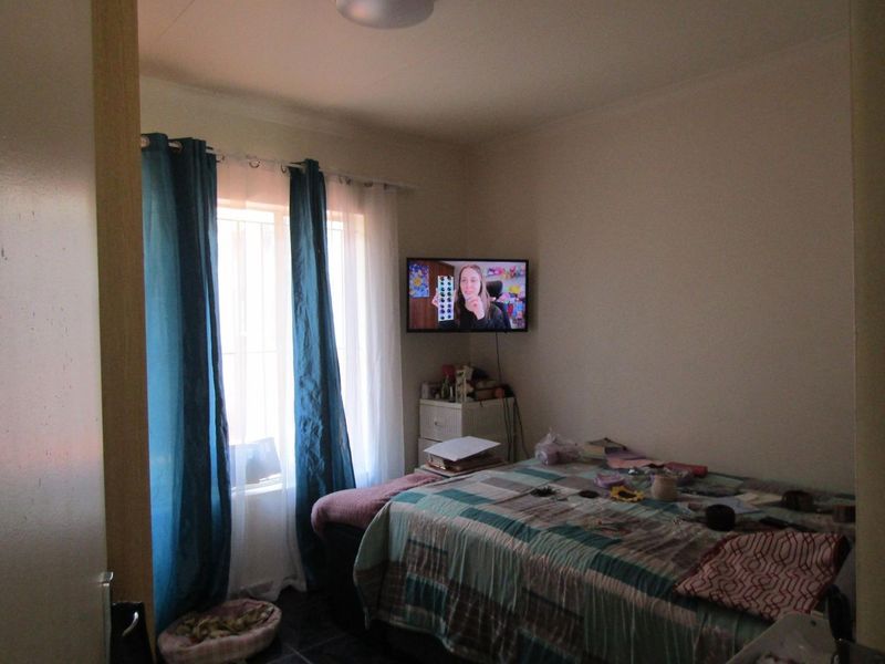 A standard bedroom featuring a wall-mounted television and window with curtains.