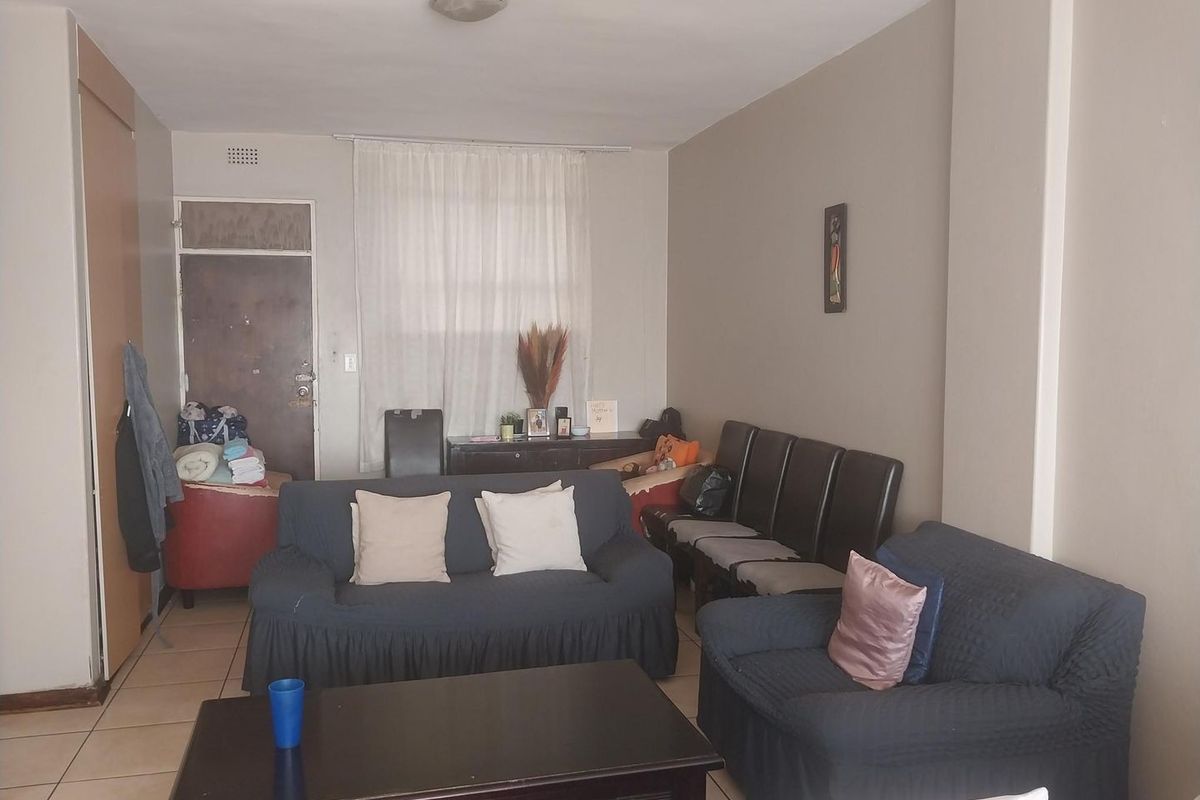A living room area featuring tiled flooring and a built-in cupboard, providing a functional space that could benefit from cosmetic updates.