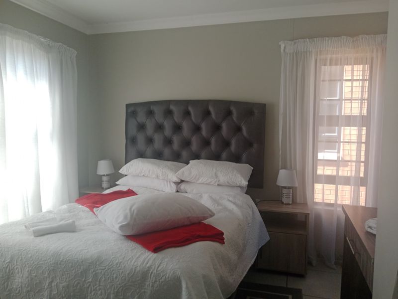A functional bedroom featuring tiled flooring and coving, with dual windows providing natural light.