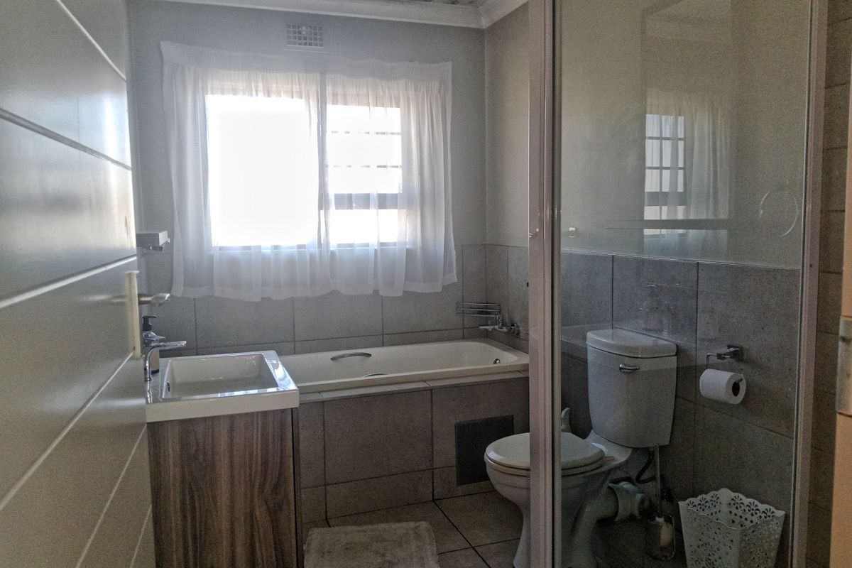 A functional bathroom featuring a built-in vanity, bathtub, and separate shower enclosure, with visible water staining on the ceiling requiring attention.