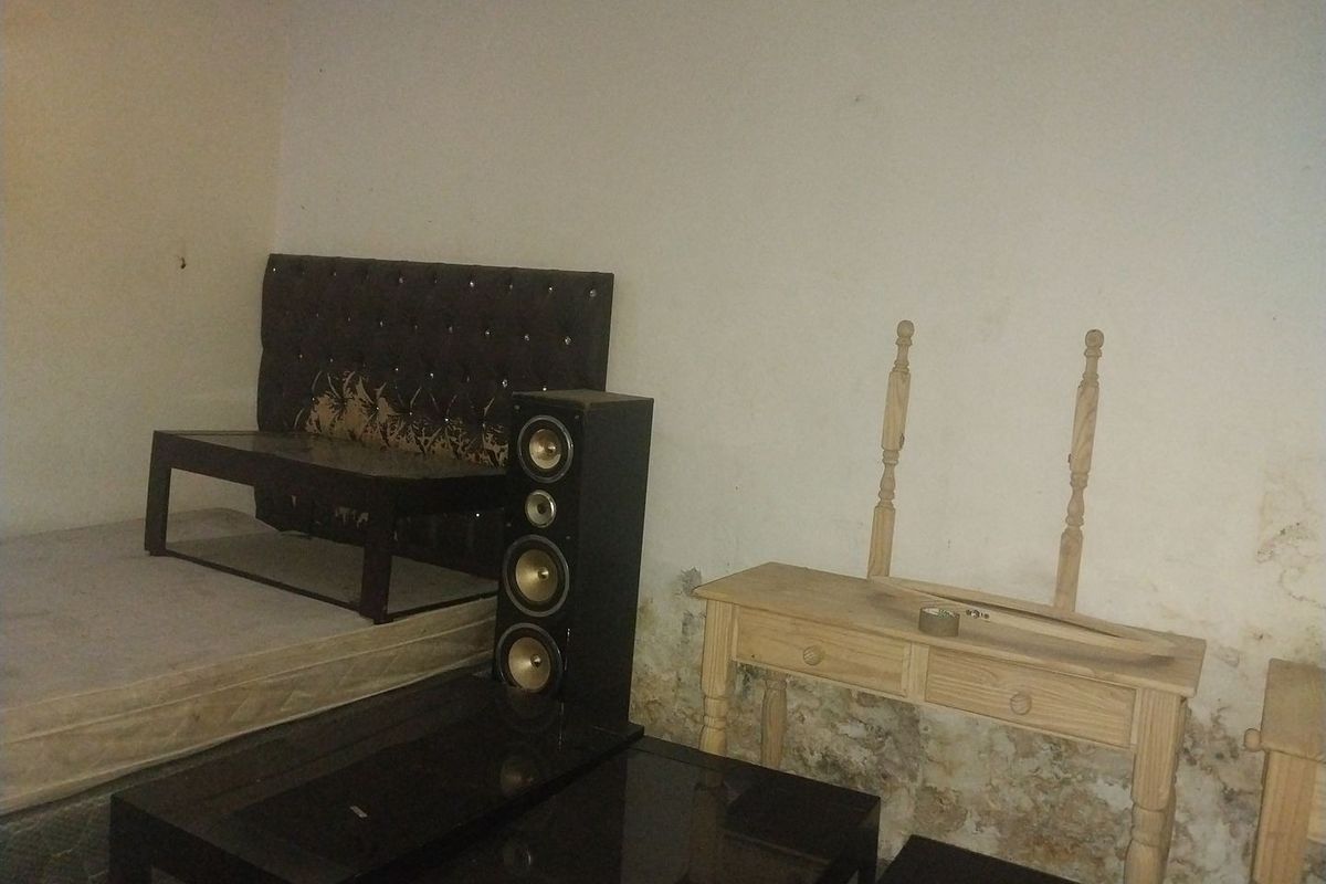 A bedroom space showing significant wall surface damage and damp staining, requiring repair and redecoration to restore the interior finish.