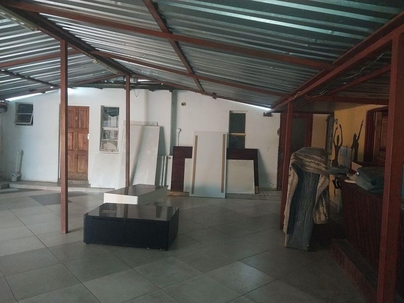 A covered outdoor patio area featuring a corrugated metal roof, steel support structure, and tiled flooring, suitable for renovation or outdoor entertainment use.