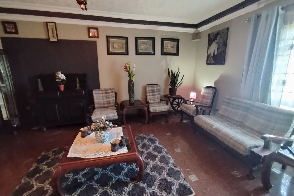 A traditional living room featuring tiled flooring and decorative ceiling cornicing, offering a comfortable and classic space for relaxation.