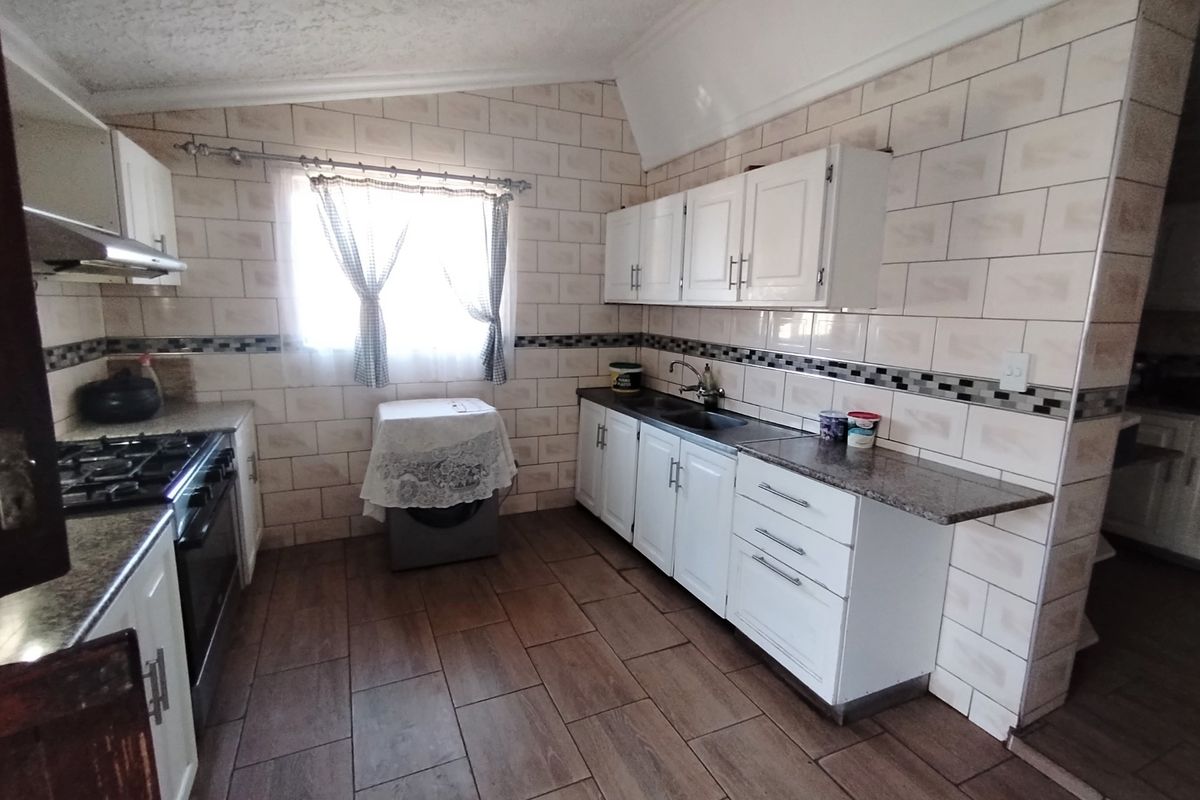 Functional kitchen featuring granite countertops, built-in cabinetry, gas hob with extractor, and tiled splashbacks, offering a practical layout for daily cooking.