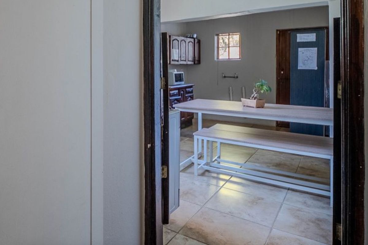 A view into a dated kitchen area featuring tiled flooring and traditional wooden cabinetry, offering potential for a modern renovation.