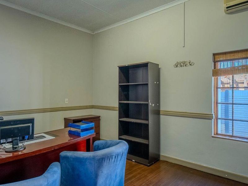 A functional home office space featuring wooden flooring, chair rail molding, and an integrated air conditioning unit.