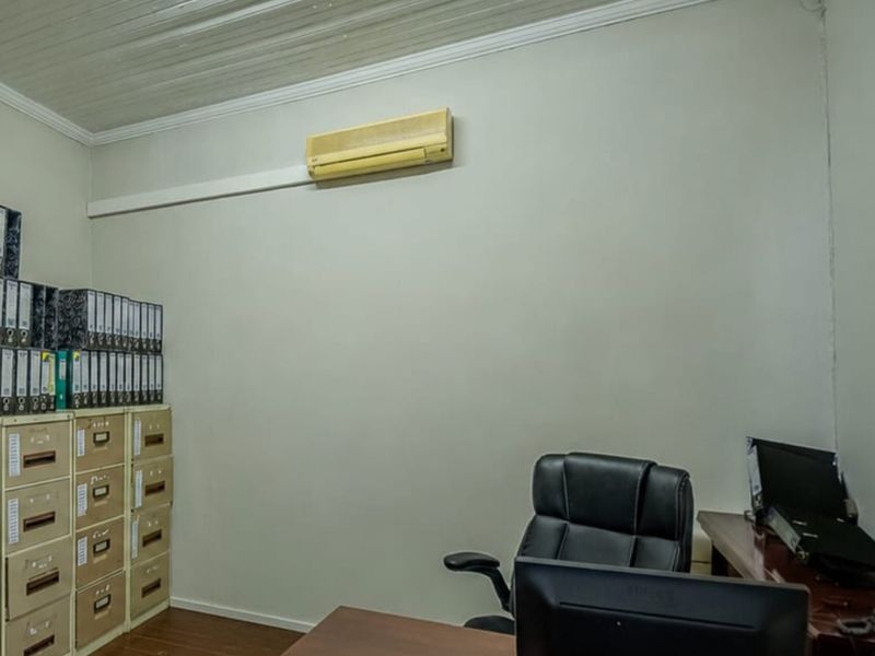 A functional office space featuring timber flooring, crown molding, and a wall-mounted air conditioning unit.