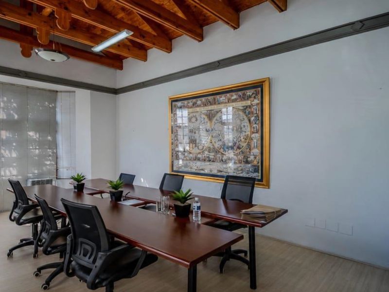 A professional office space featuring exposed timber ceiling beams, laminate flooring, and large windows with fitted venetian blinds.