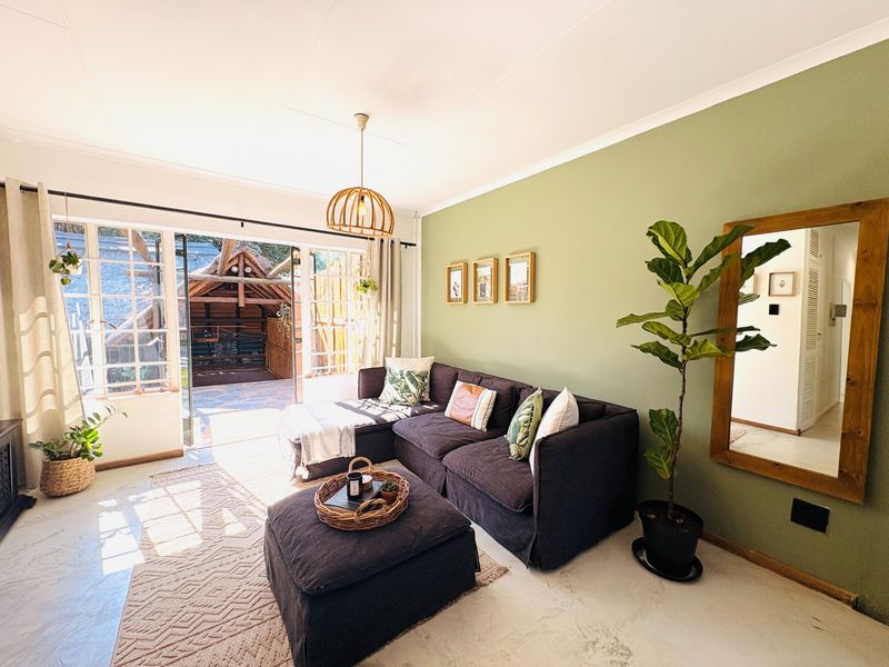 Bright living room featuring polished concrete floors, a feature green wall, and large sliding glass doors opening to an outdoor patio area.