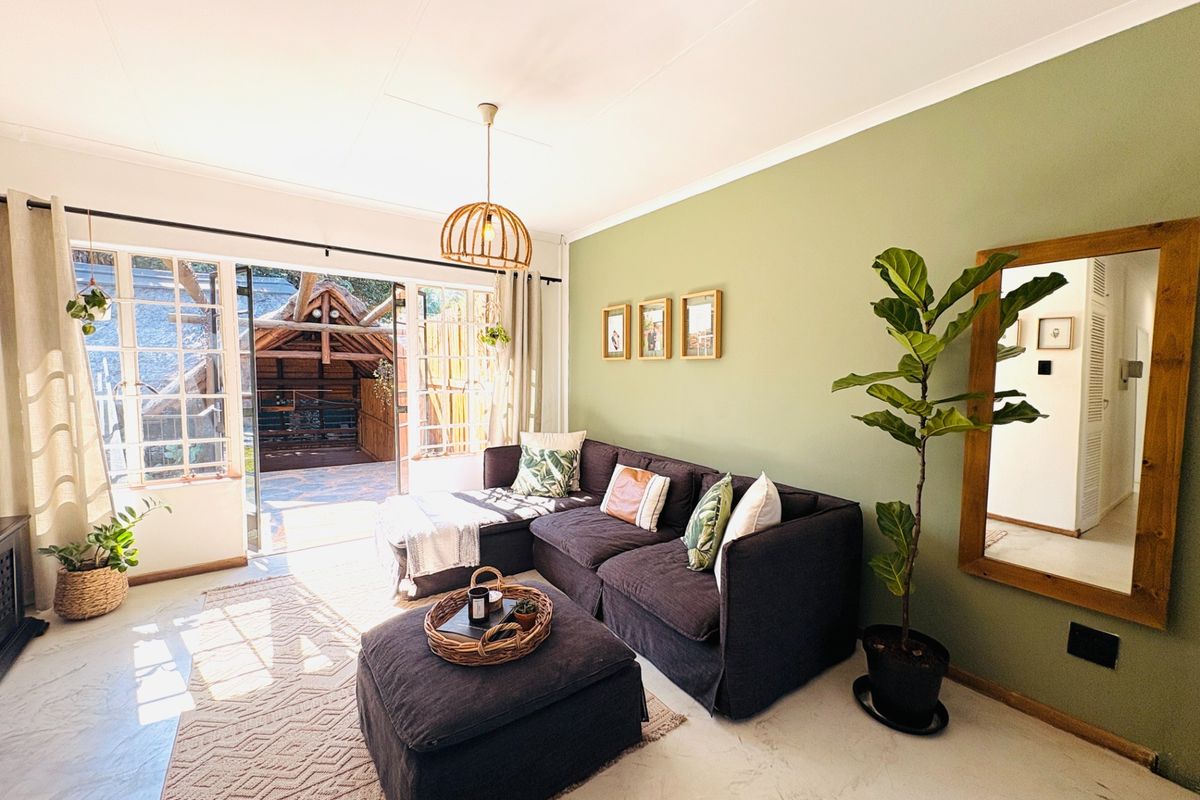 Bright living room featuring polished concrete floors, a feature green wall, and large sliding glass doors opening to an outdoor patio area.